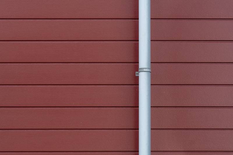 A downspout fastened to a wall of horizontal lap siding